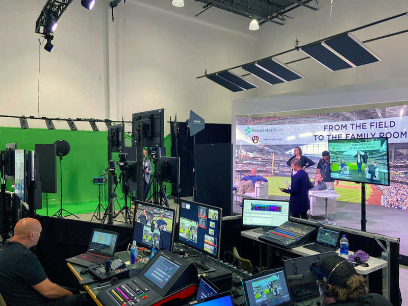 people standing in a studio production set with cameras, green screens, and computer monitors