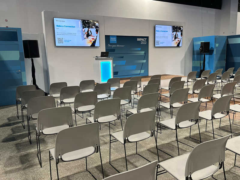 a small stage set up with chairs, a podium, and brand signage